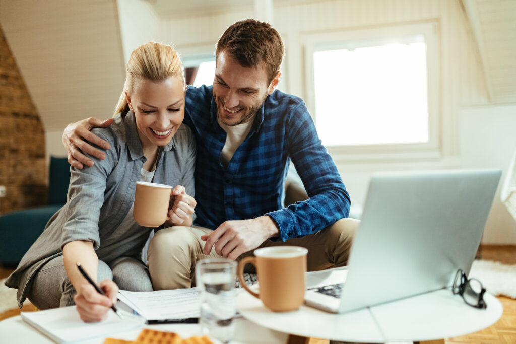 Singapore Best Personal Loans for Foreigners & Expats (2025) 1 Young happy couple working on home budget while drinking coffee in the living room.