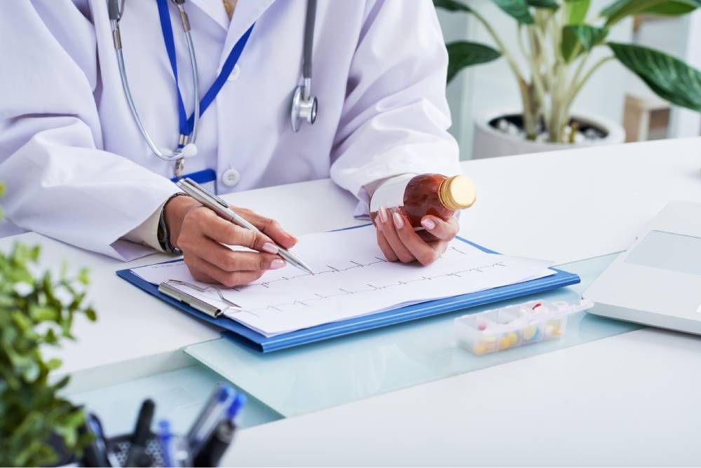 hands female doctor looking cardiogram holding bottle medicine